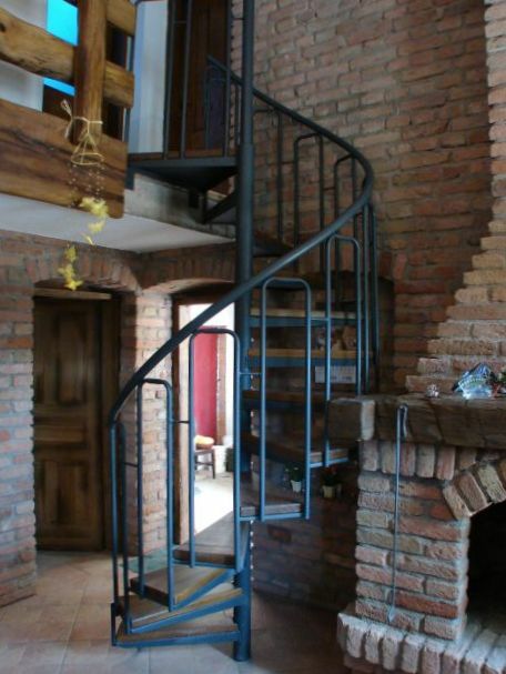 Metalne spiralne stepenice u interijeru s drvenim oblogama